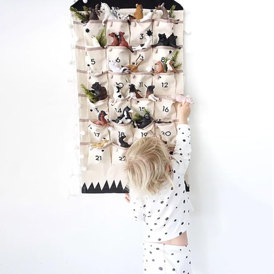 Child reaching into a pocket of the wall-hung advent calendar