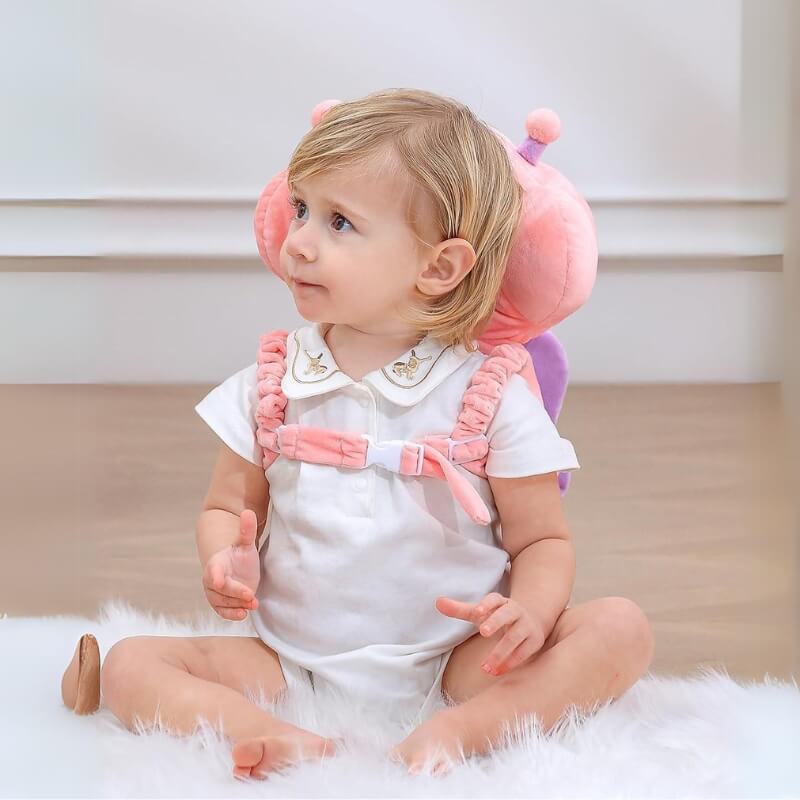 Baby sitting upright wearing the pink butterfly head protector