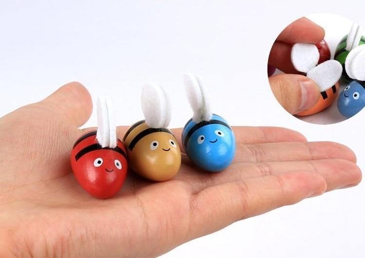 Three small wooden bees resting in an adult's palm
