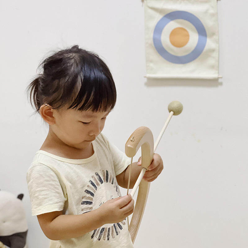 Child aiming the wooden bow at the hanging fabric target