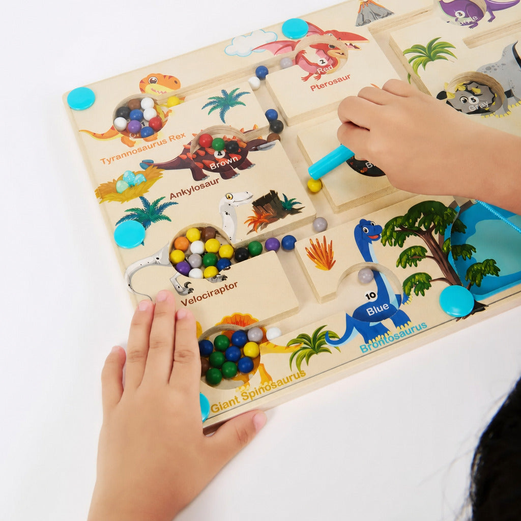 Small hand guiding magnetic beads across the dinosaur board