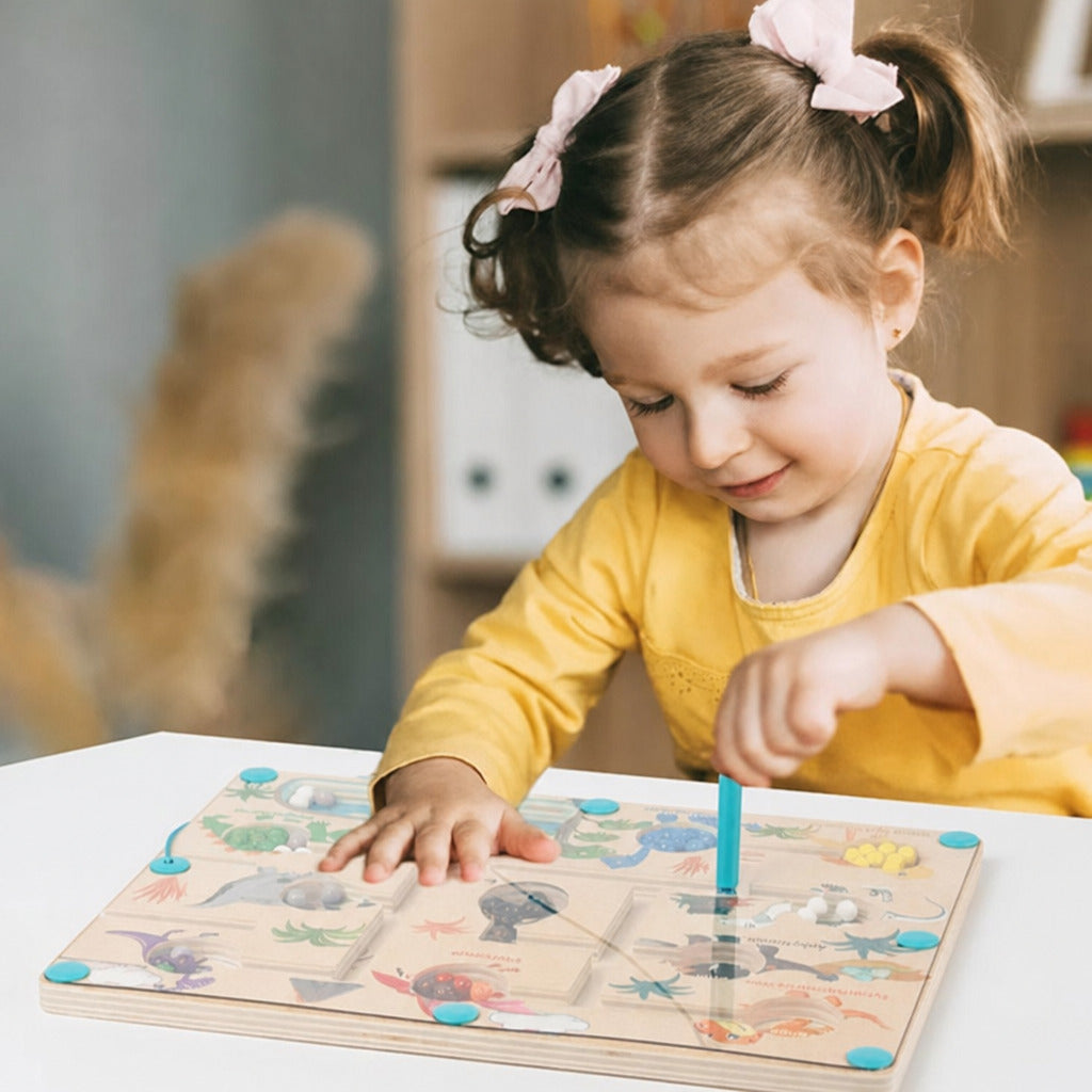 Girl concentrating on the dinosaur magnetic maze at a table