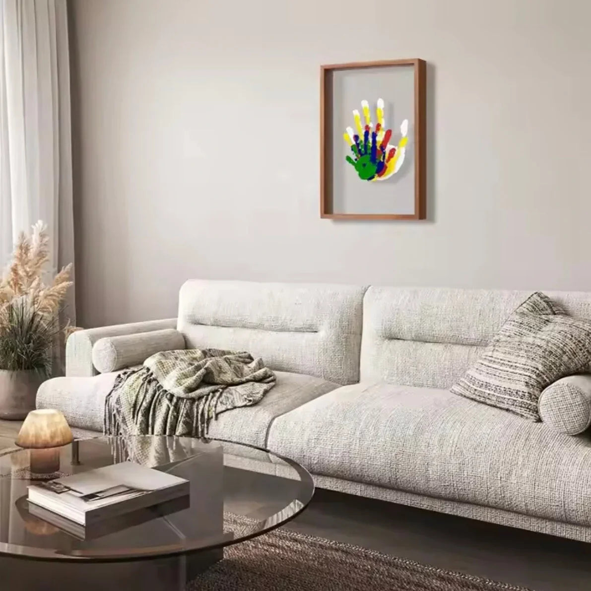 Handprint keepsake frame hung on a wall above a sofa