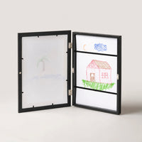 Black art frame opened to show the drawing storage compartment