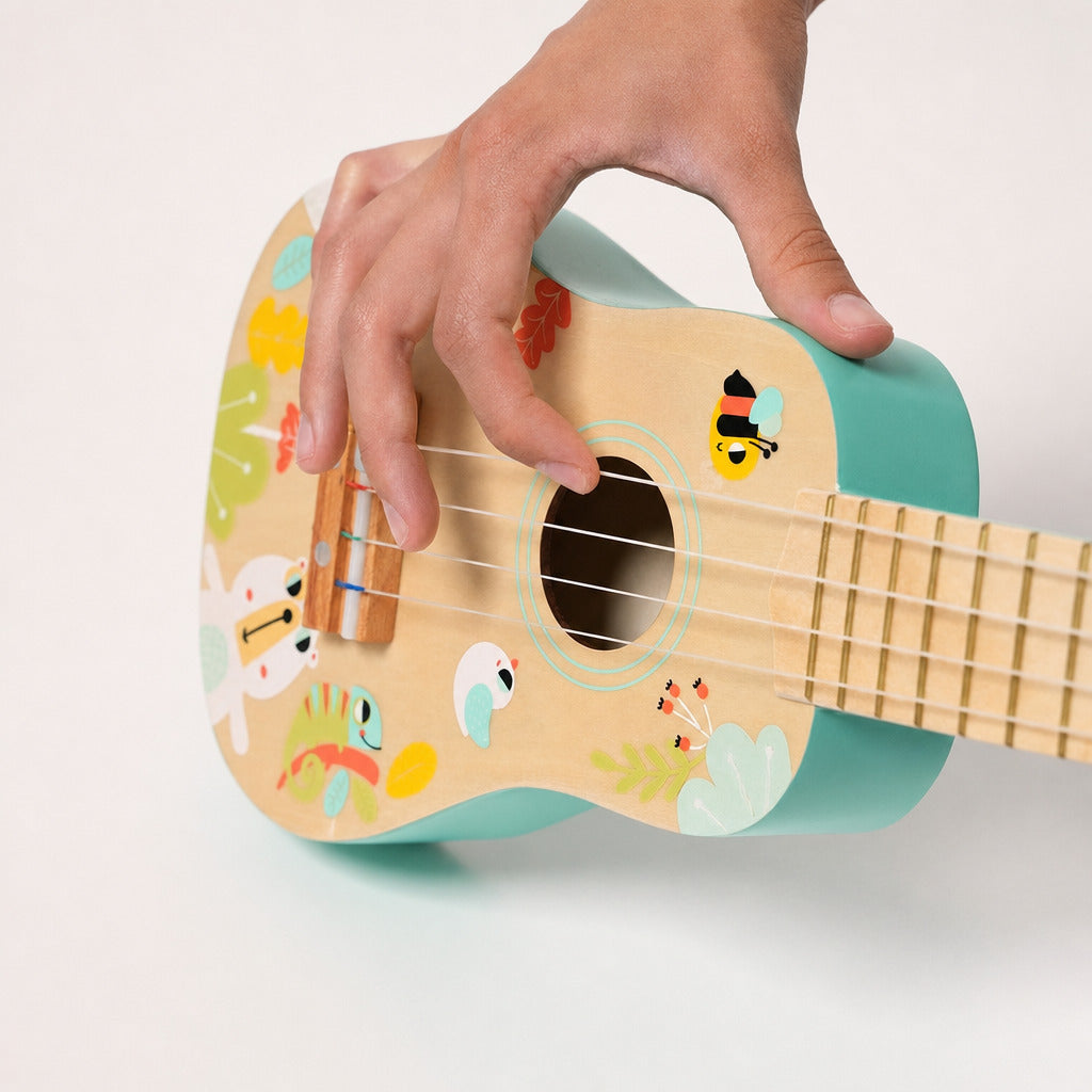 Child playing the turquoise wooden four-string ukulele