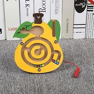 Yellow bear magnetic maze standing on a carpet beside books