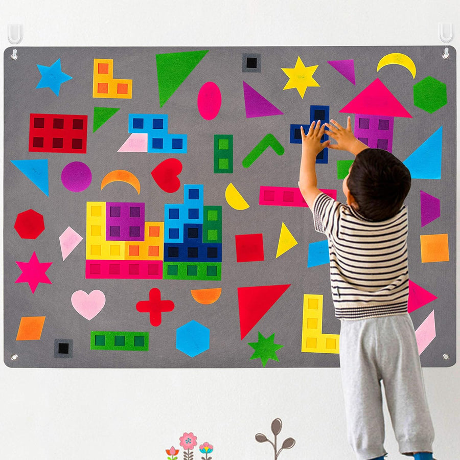 Child placing felt shapes on the large grey wall felt board