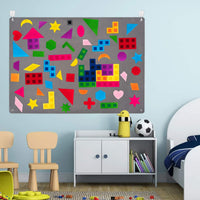 Felt board mounted on a playroom wall covered in coloured shapes