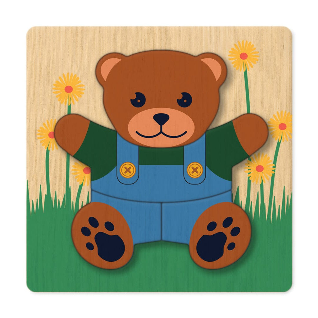 Teddy bear layered wooden puzzle in dungarees on a grass background