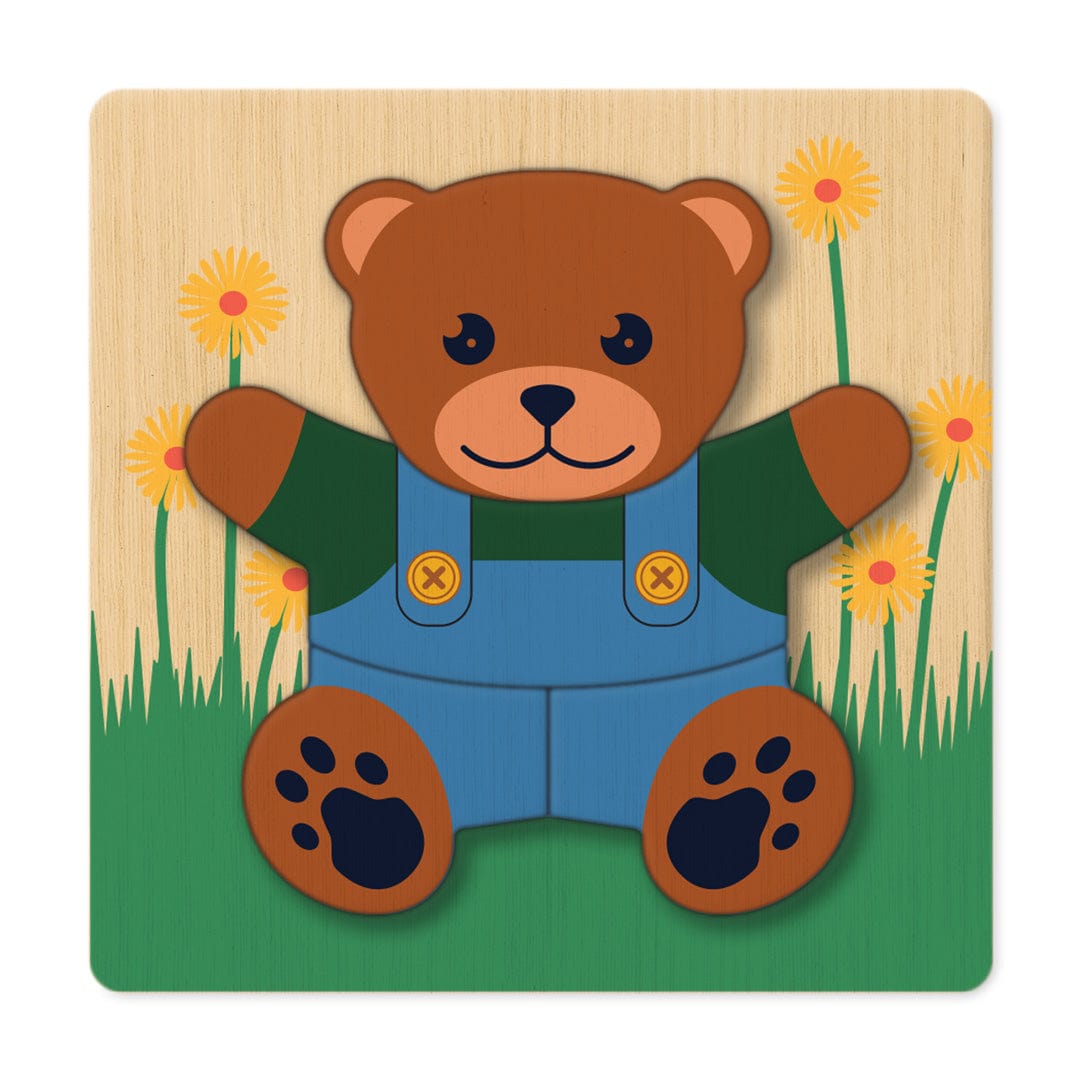 Teddy bear layered wooden puzzle in dungarees on a grass background