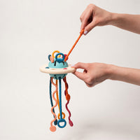 Child pulling the coloured cords of the silicone Montessori toy