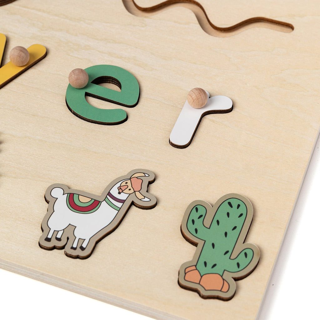 Close-up of raised letters and llama piece on a wooden name puzzle