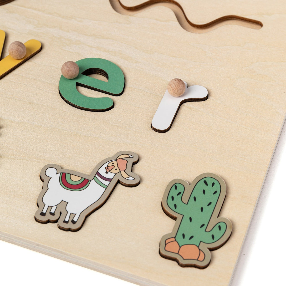 Close-up of raised letters and llama piece on a wooden name puzzle