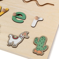 Close-up of raised letters and llama piece on a wooden name puzzle