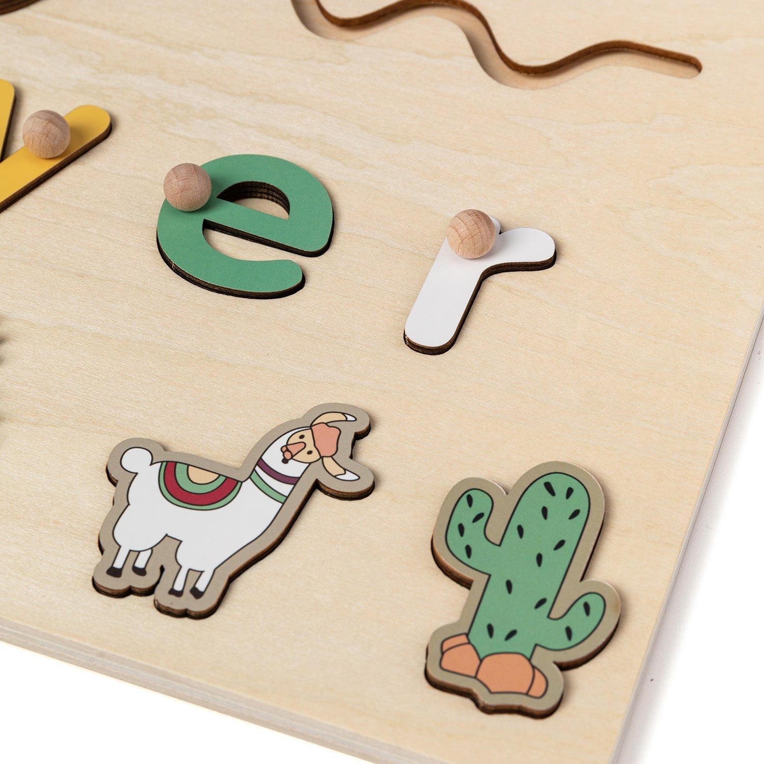 Close-up of raised letters and llama piece on a wooden name puzzle