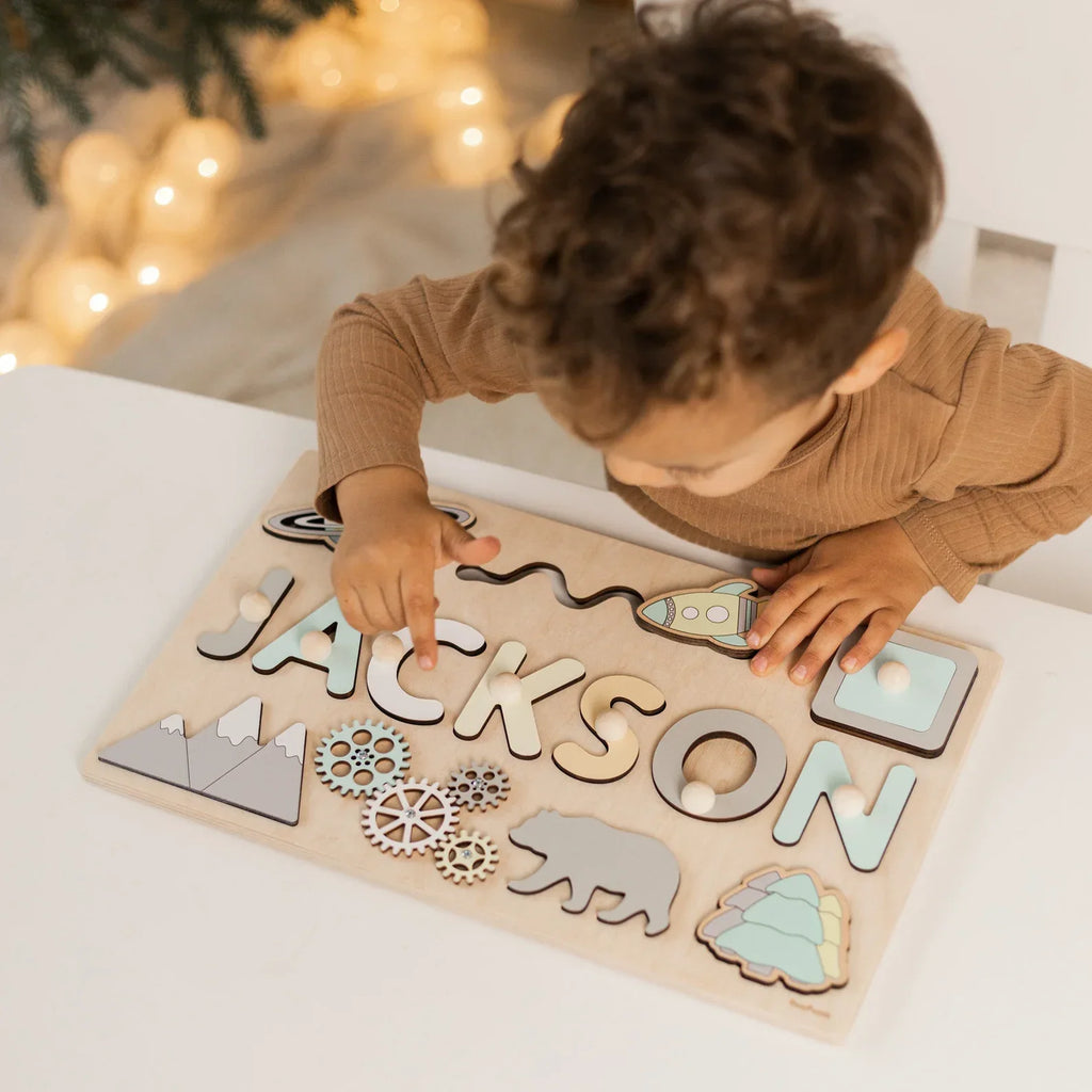 Boy fitting letters into a wooden name puzzle spelling Jackson