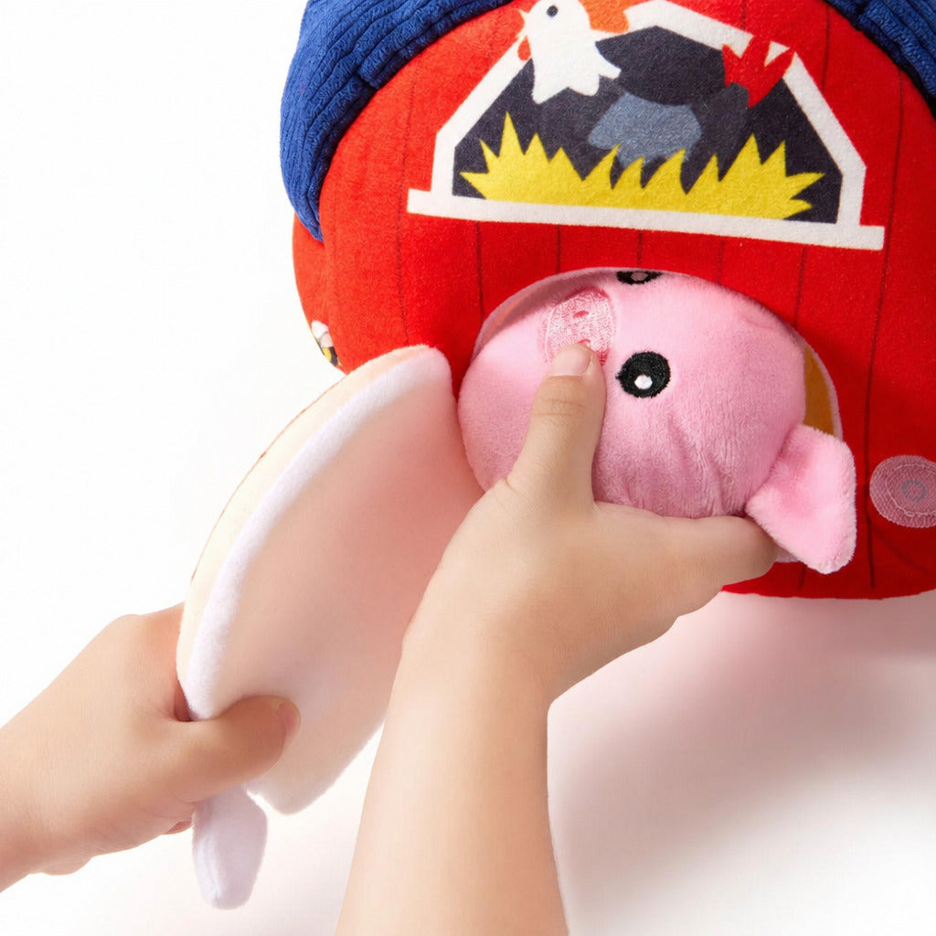 Child pulling a pink plush animal out of the soft barn