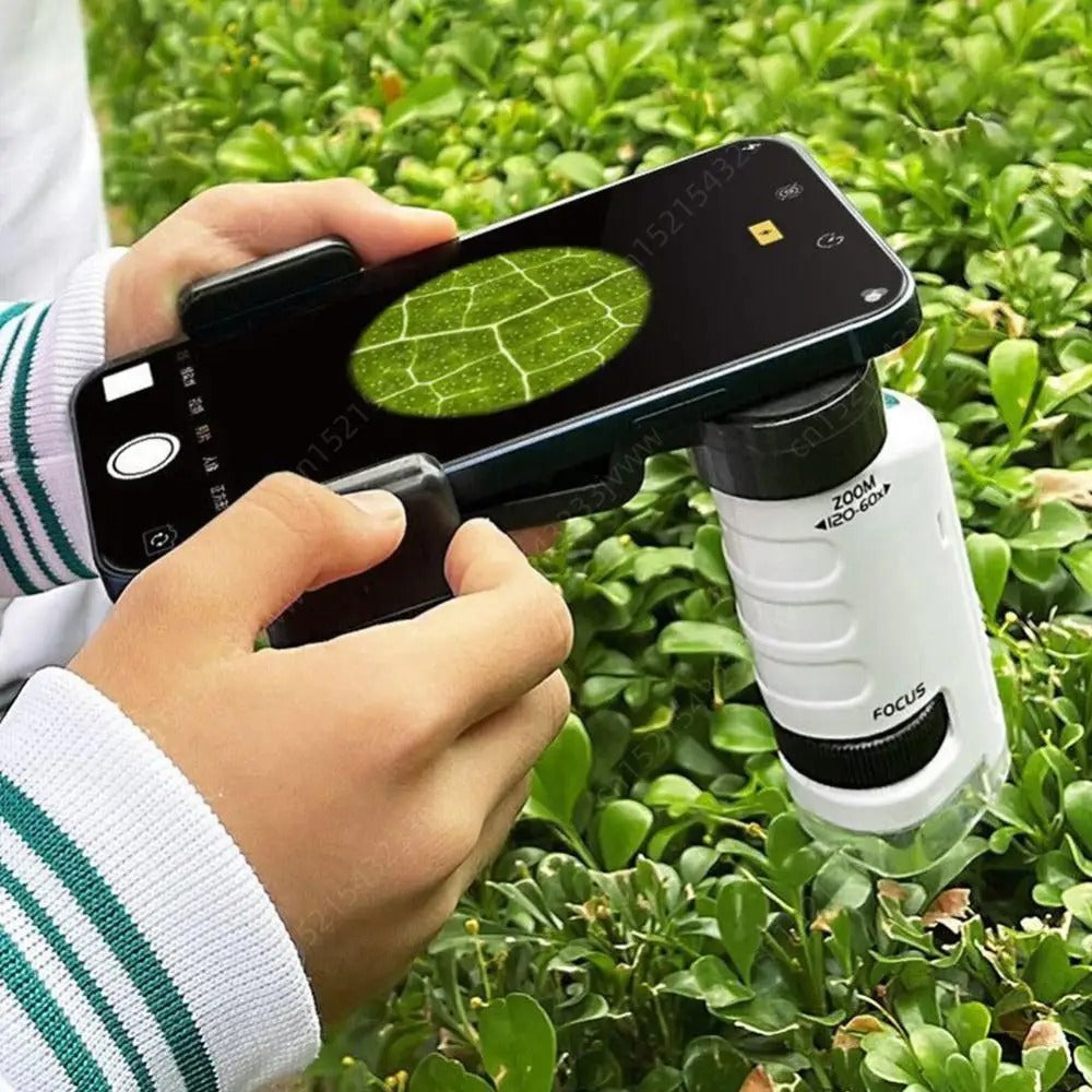 Child holding a phone against the microscope to photograph a leaf