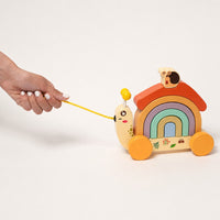 Child pulling the wooden snail toy along by its cord