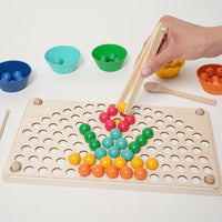 Child placing coloured beads on the pegboard with wooden tweezers