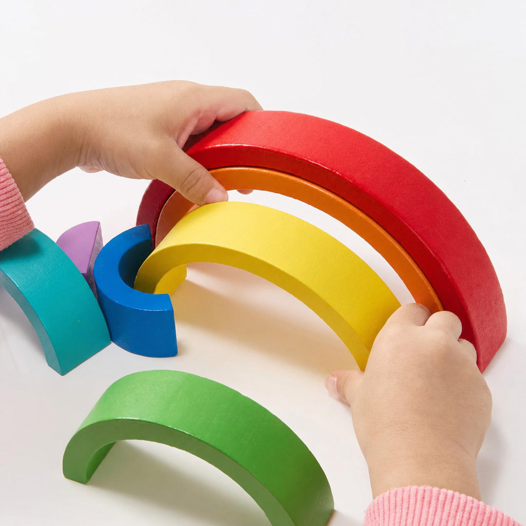 Child lifting the red arch from the wooden rainbow stacker