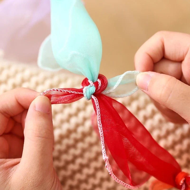 Hands knotting a red scarf before loading it into the cube