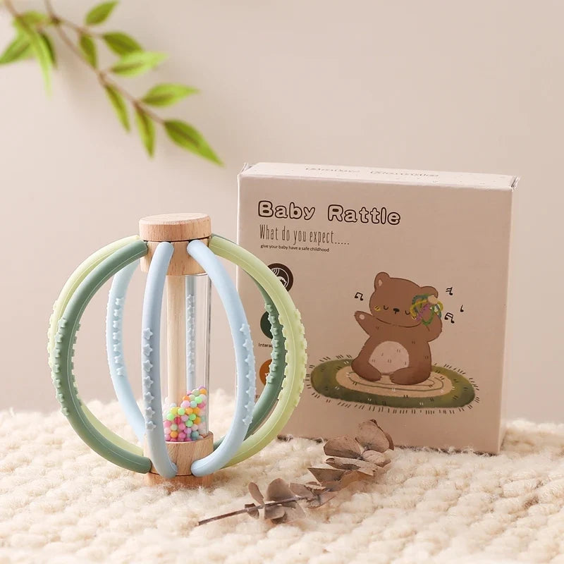 Green silicone teething rattle ball beside its Baby Rattle box