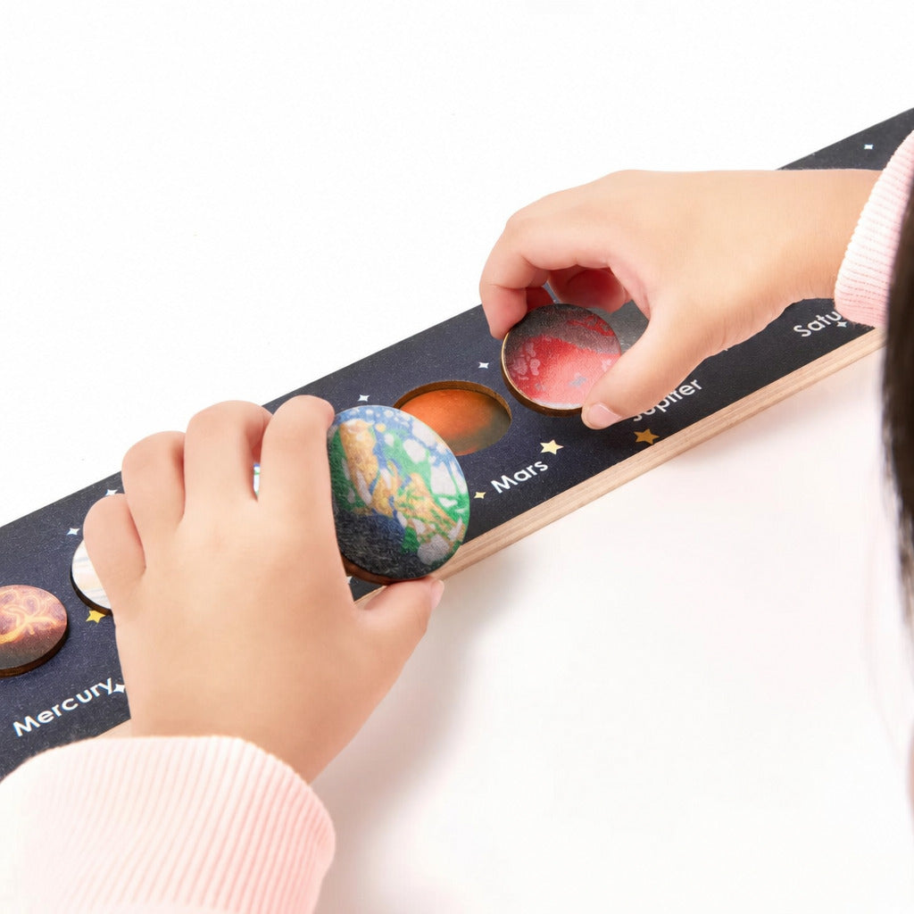 Child lifting a planet knob from the solar system board