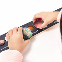 Child lifting a planet knob from the solar system board