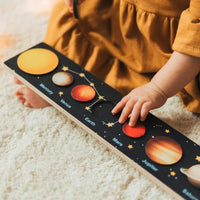 Toddler running a hand along the solar system puzzle strip