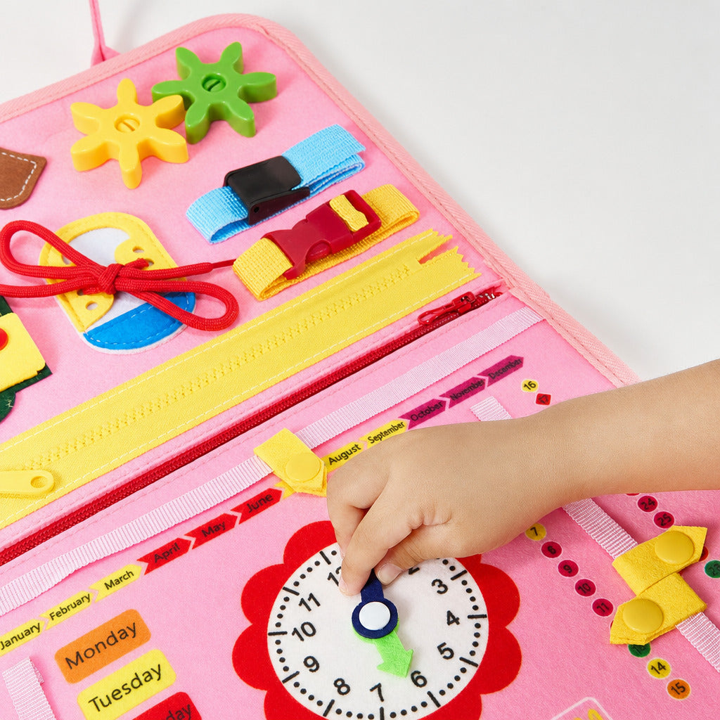 Child turning the clock hands on the open pink busy board
