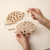Two hands lacing cord through the hedgehog's holes