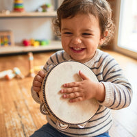 Toddler laughing while holding a wooden tambourine