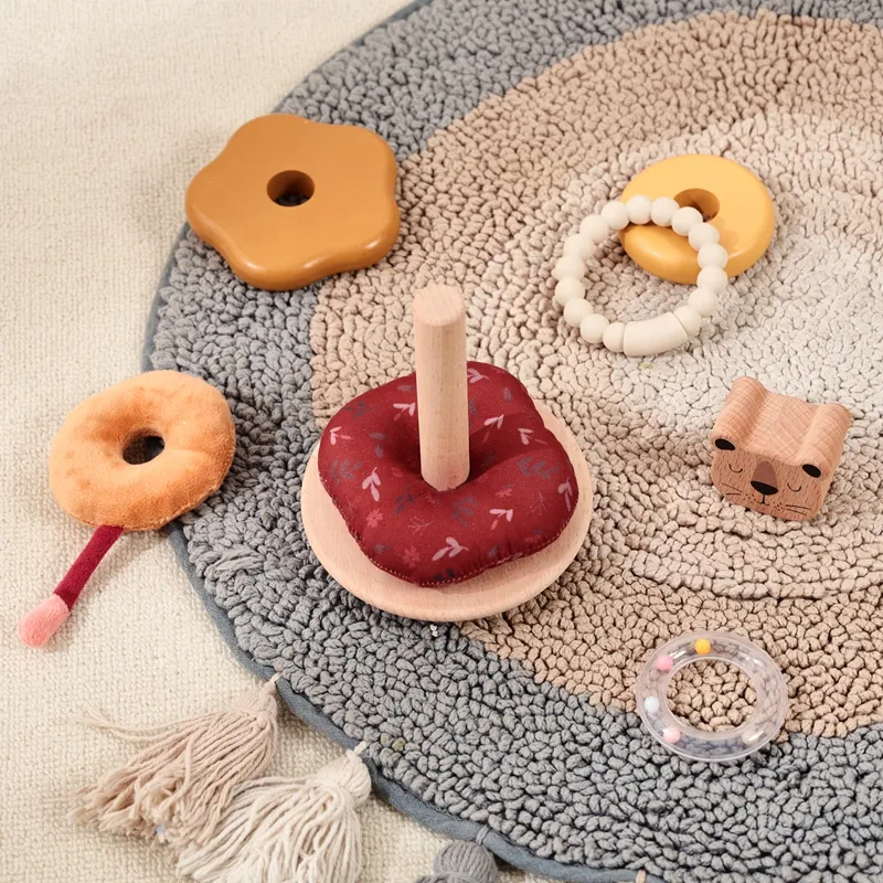 Wooden stacking rings and teethers arranged on a textured rug