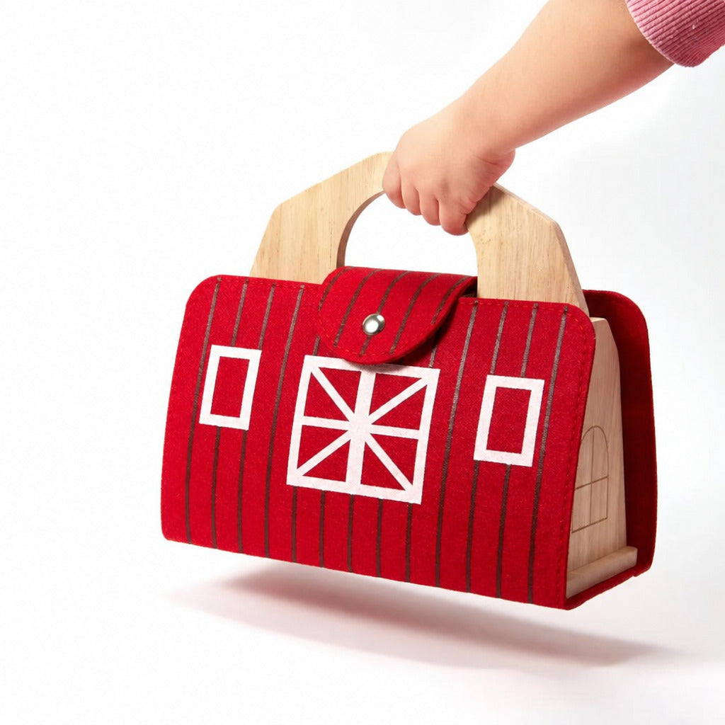 Child carrying the red wooden barn by its handle