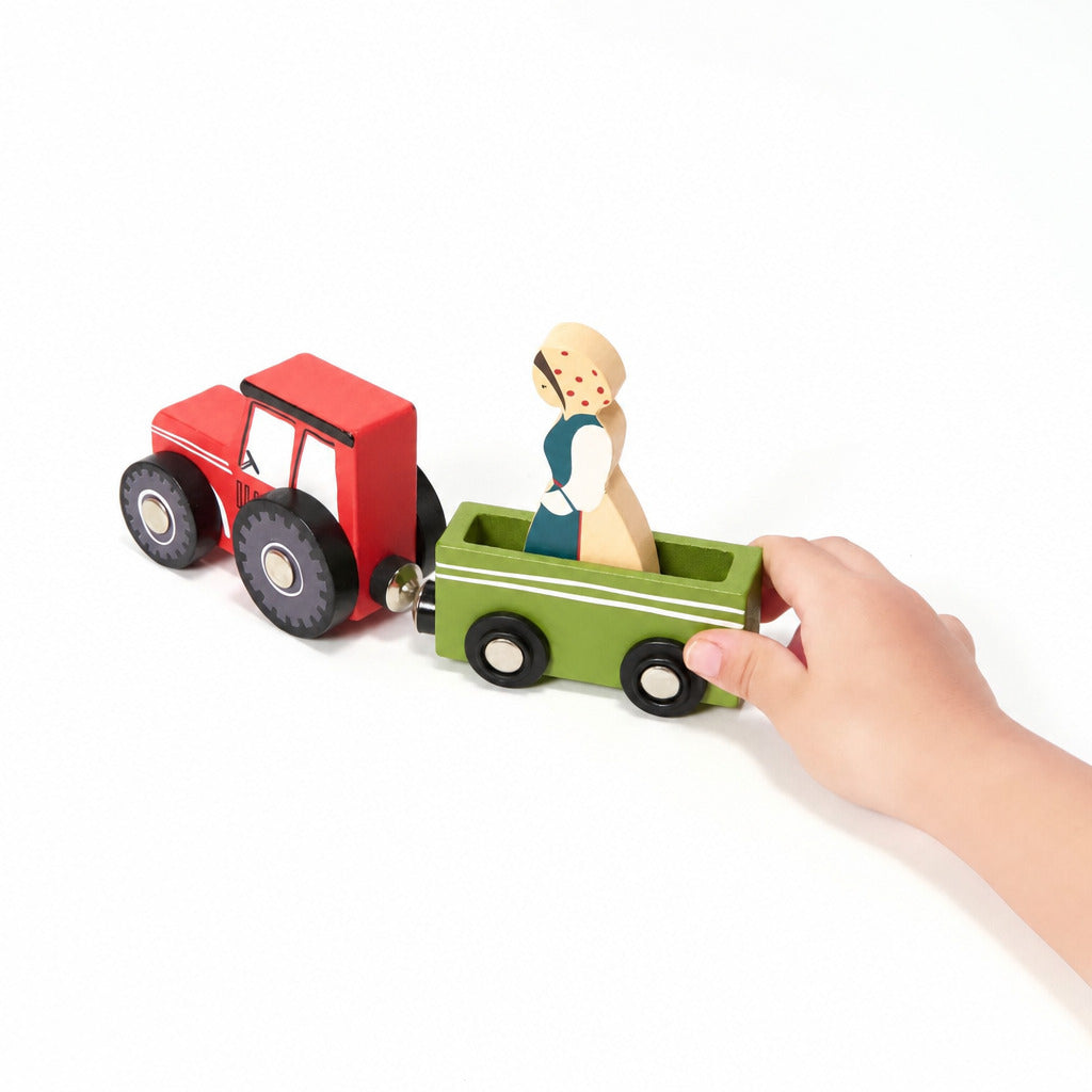 Child's hand pushing the wooden tractor and trailer with a farmer