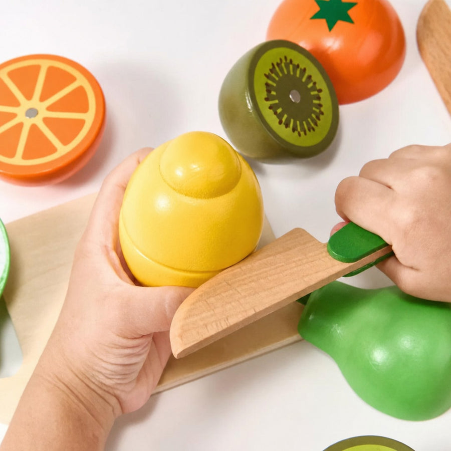 Child slicing a wooden pear with a play knife