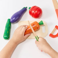Child cutting a wooden carrot on a small chopping board