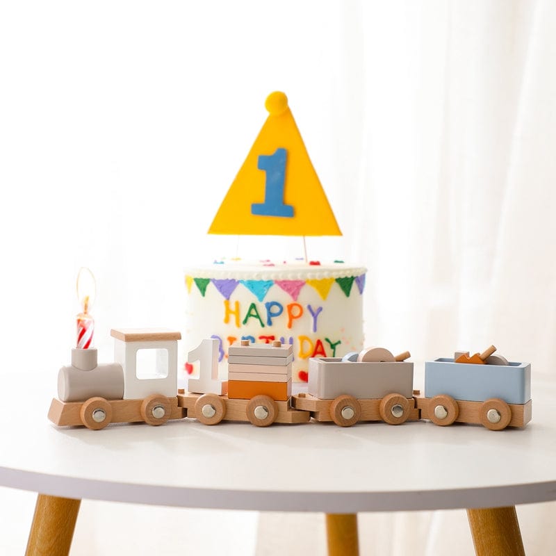 Wooden number train arranged around a first birthday cake