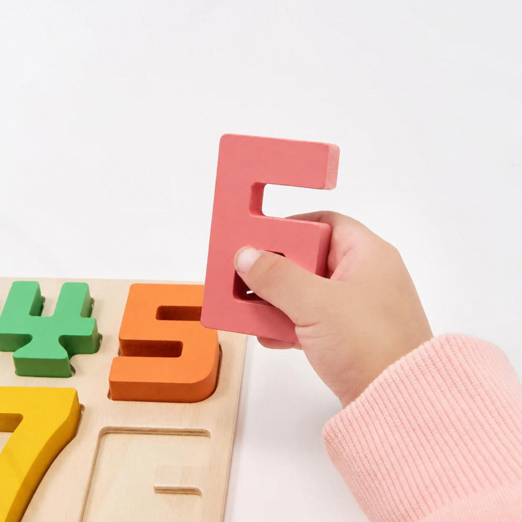 Child fitting the numeral five into the wooden number board