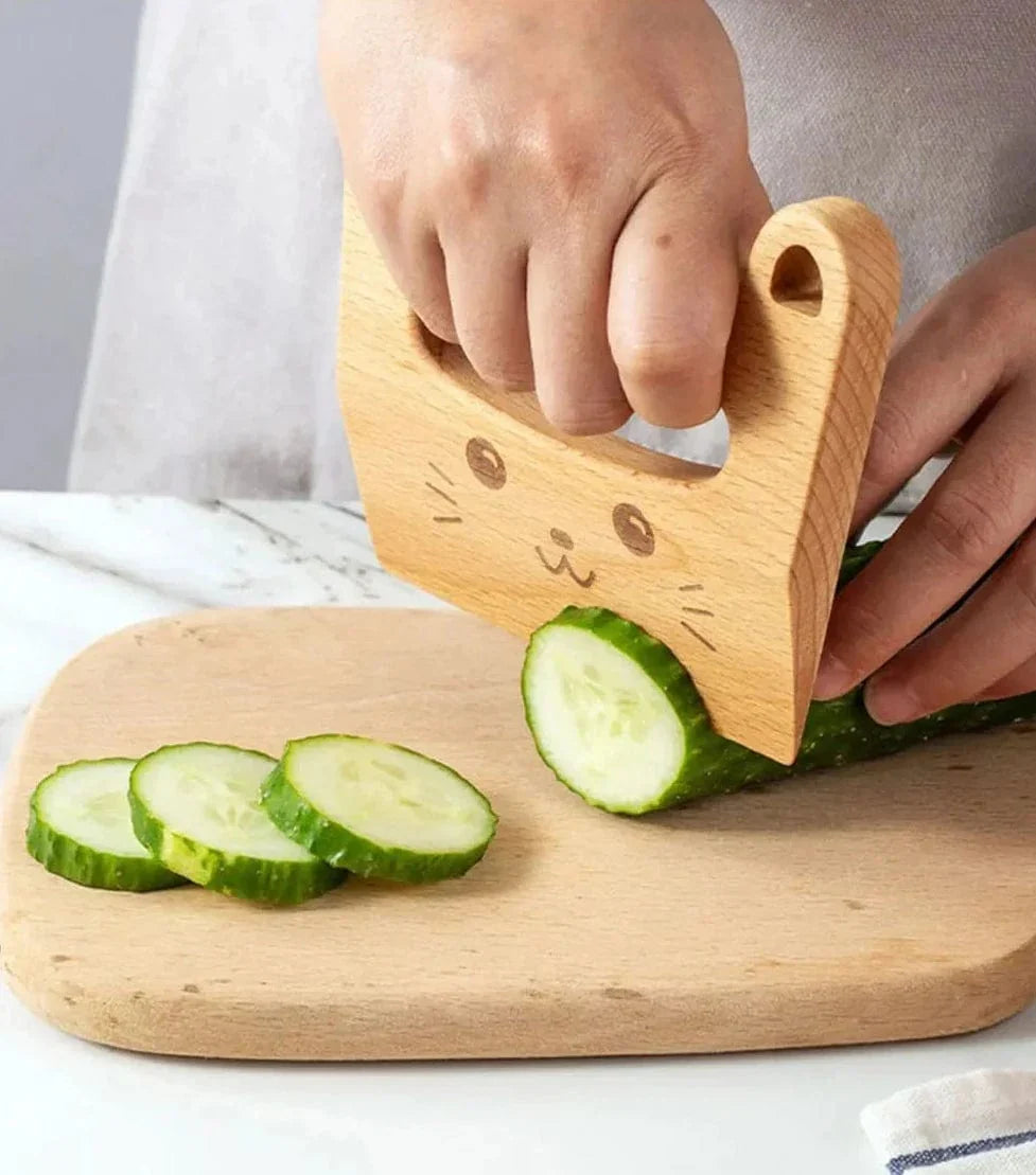Cat-shaped wooden knife slicing cucumber on a chopping board