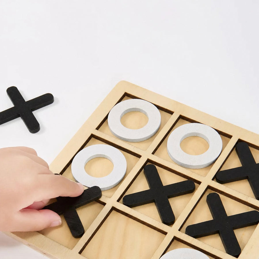 Child placing a black cross piece on the wooden tic tac toe board