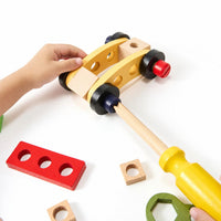 Child tightening a bolt on a wooden car with the toy screwdriver